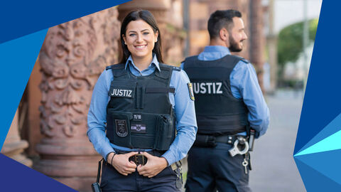 Justizwachtmeisterin und Justizwachtmeister stehen vor dem Gerichtsgebäude.