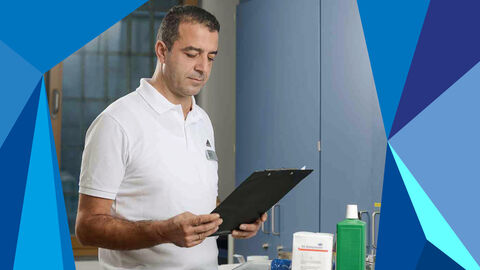 Justizsvollzugs-Mitarbeiter steht mit einem Klemmbrett vor einer Zelle.