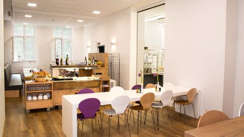 Innenansicht Mensa mit Tisch, Stühlen und Buffet